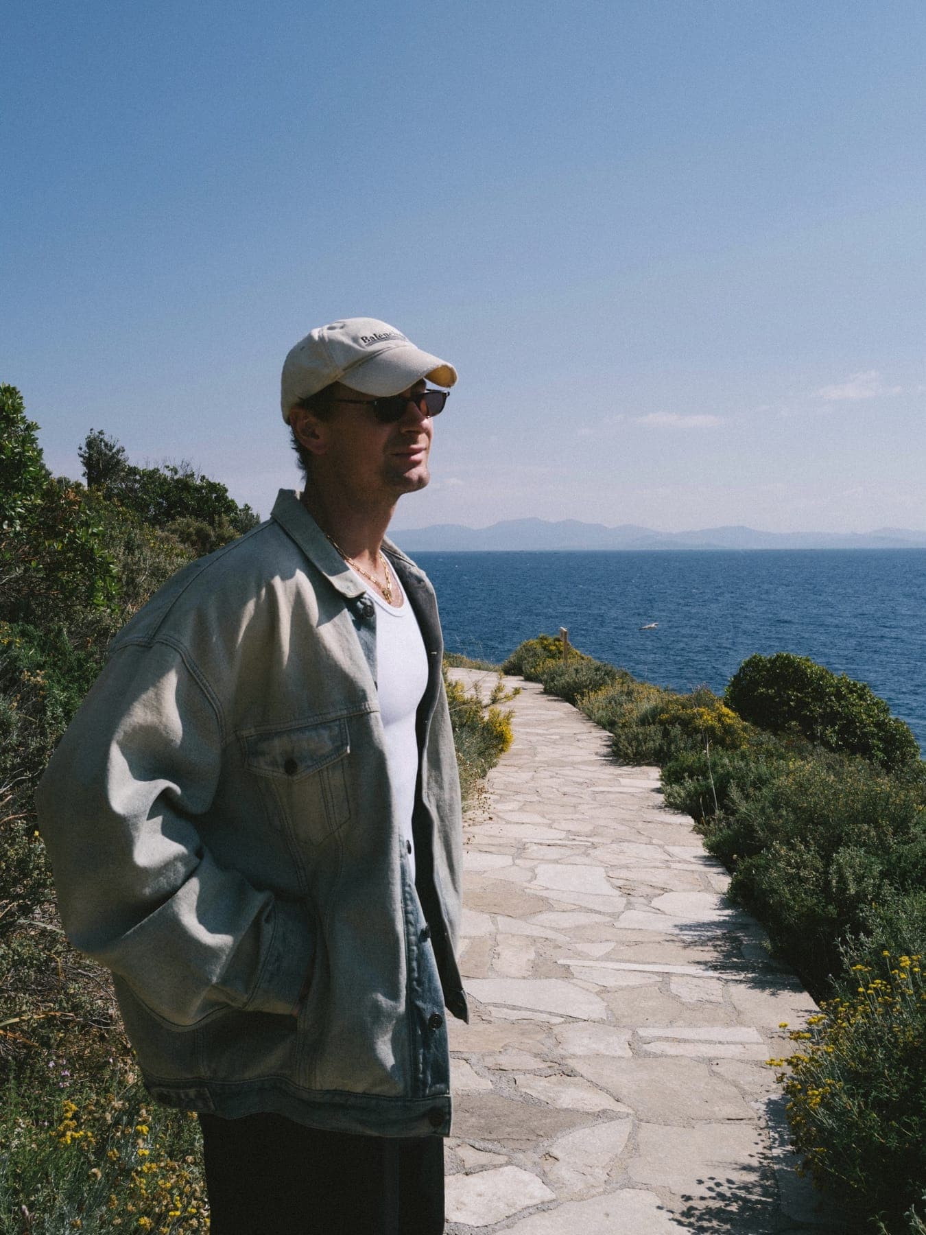 Person walking a stone path above the sea