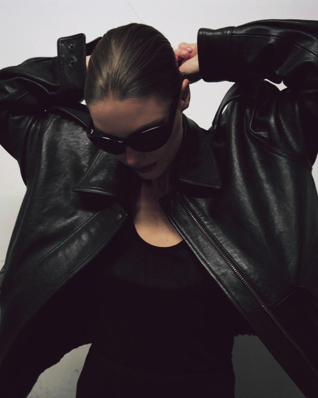 Person in a black leather jacket and sunglasses