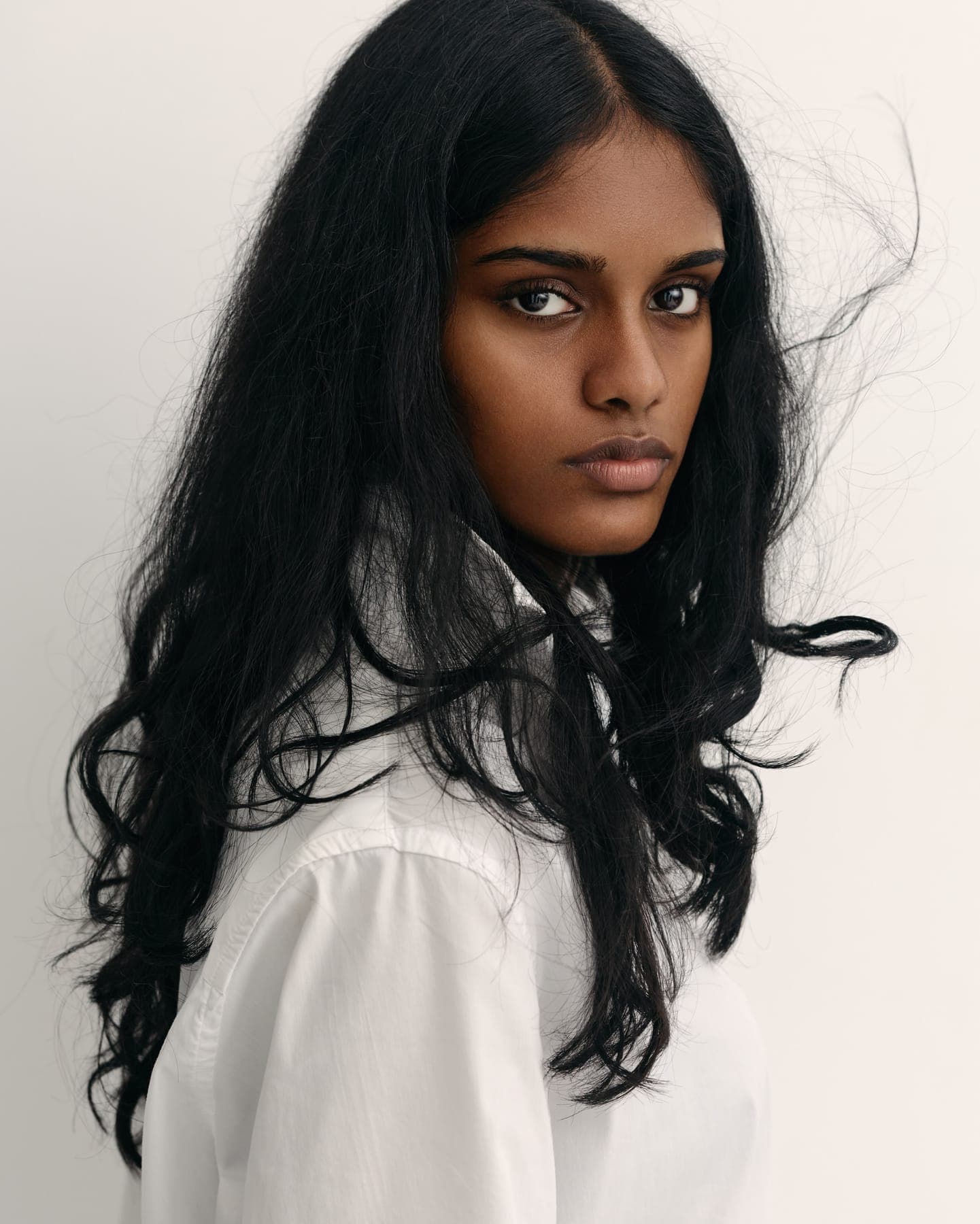 Portrait of a person with long dark hair in a white shirt