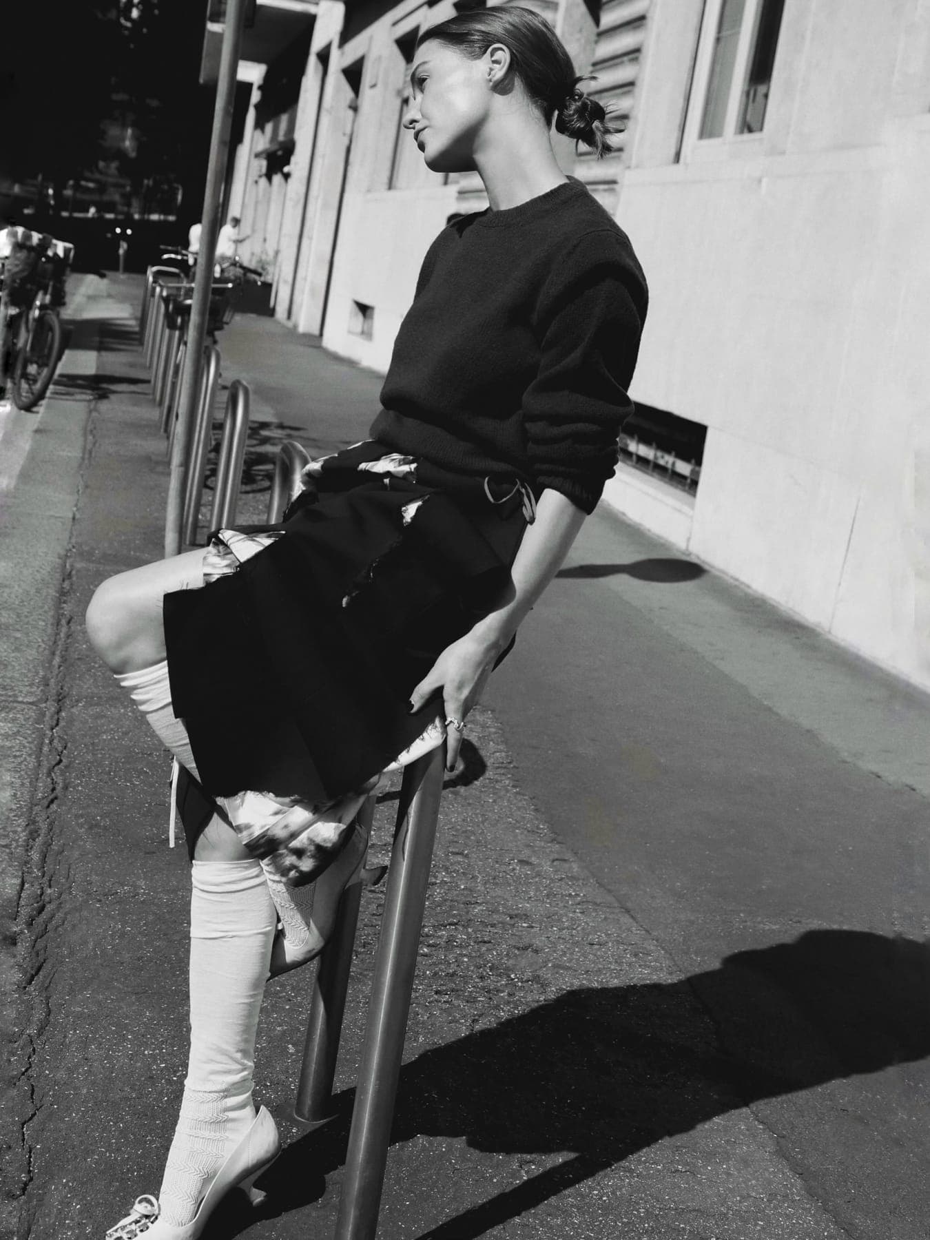Person leaning on a street rail in a black jumper