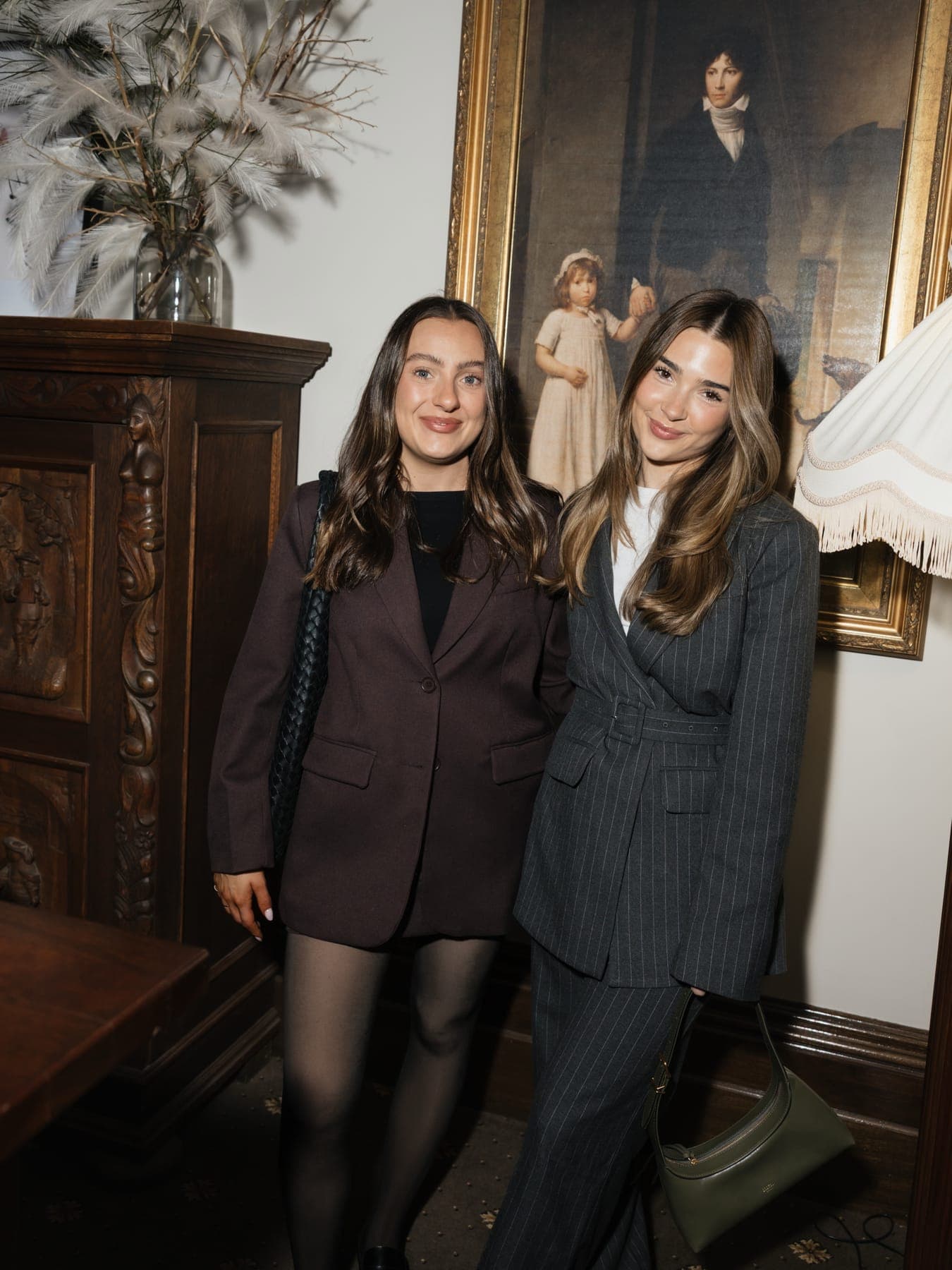 Two people in tailored suits in a wood-panelled room